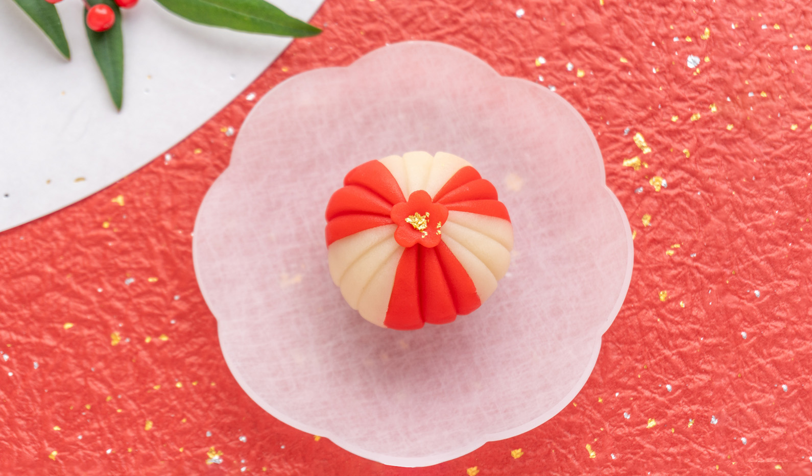 赤い和紙の上に置かれた白い皿の上に紅白の和菓子が乗っている画像